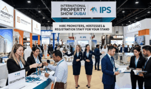 Professional promoters and hostesses assisting visitors at the registration desk during the International Property Show Dubai, welcoming real estate investors and exhibitors at a modern exhibition booth in Dubai.